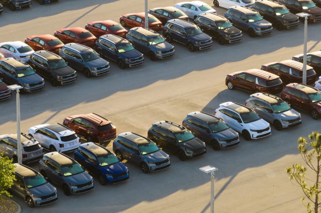 inventory management for car dealerships - Large parking lot of local dealer with many brand new cars parked for sale.